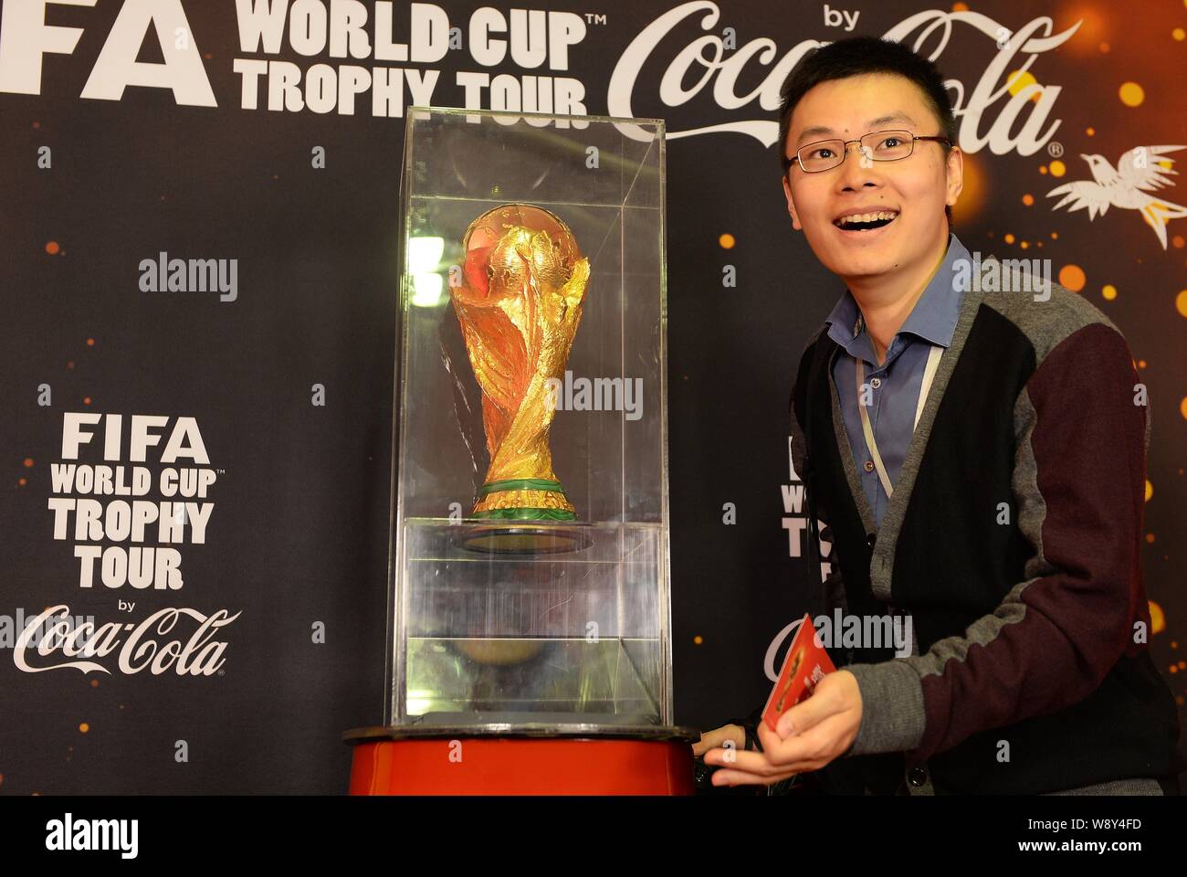 Un visitatore cinese pone con una replica della FIFA World Cup Trofeo durante il FIFA World Cup Trophy Tour in Cina a Shanghai, 9 aprile 2014. Foto Stock