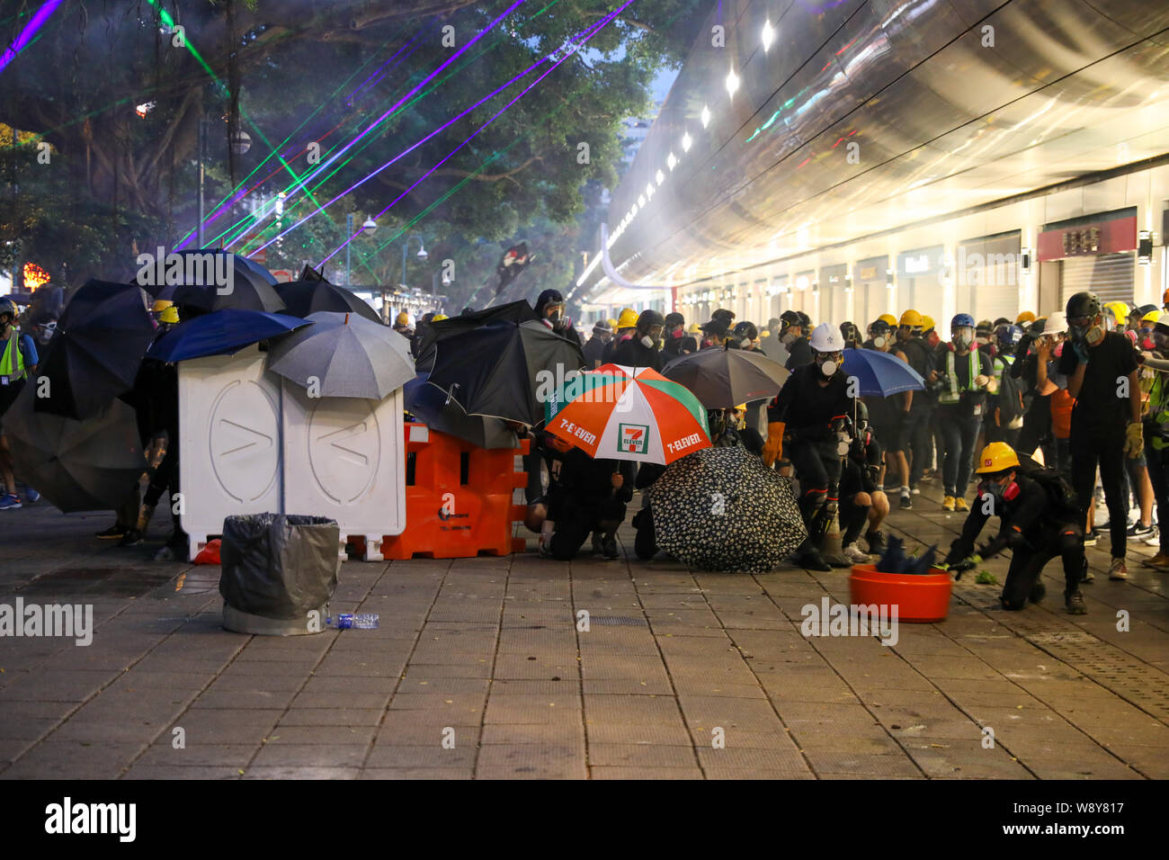 11 agosto 2019 Hong Kong. Manifestanti tenendo il coperchio dietro barricate e ombrelloni come fuoco di polizia gas lacrimogeni e pallottole di gomma da Tsim Sha Tsui stazione di polizia durante un anti extradition bill protesta. Foto Stock