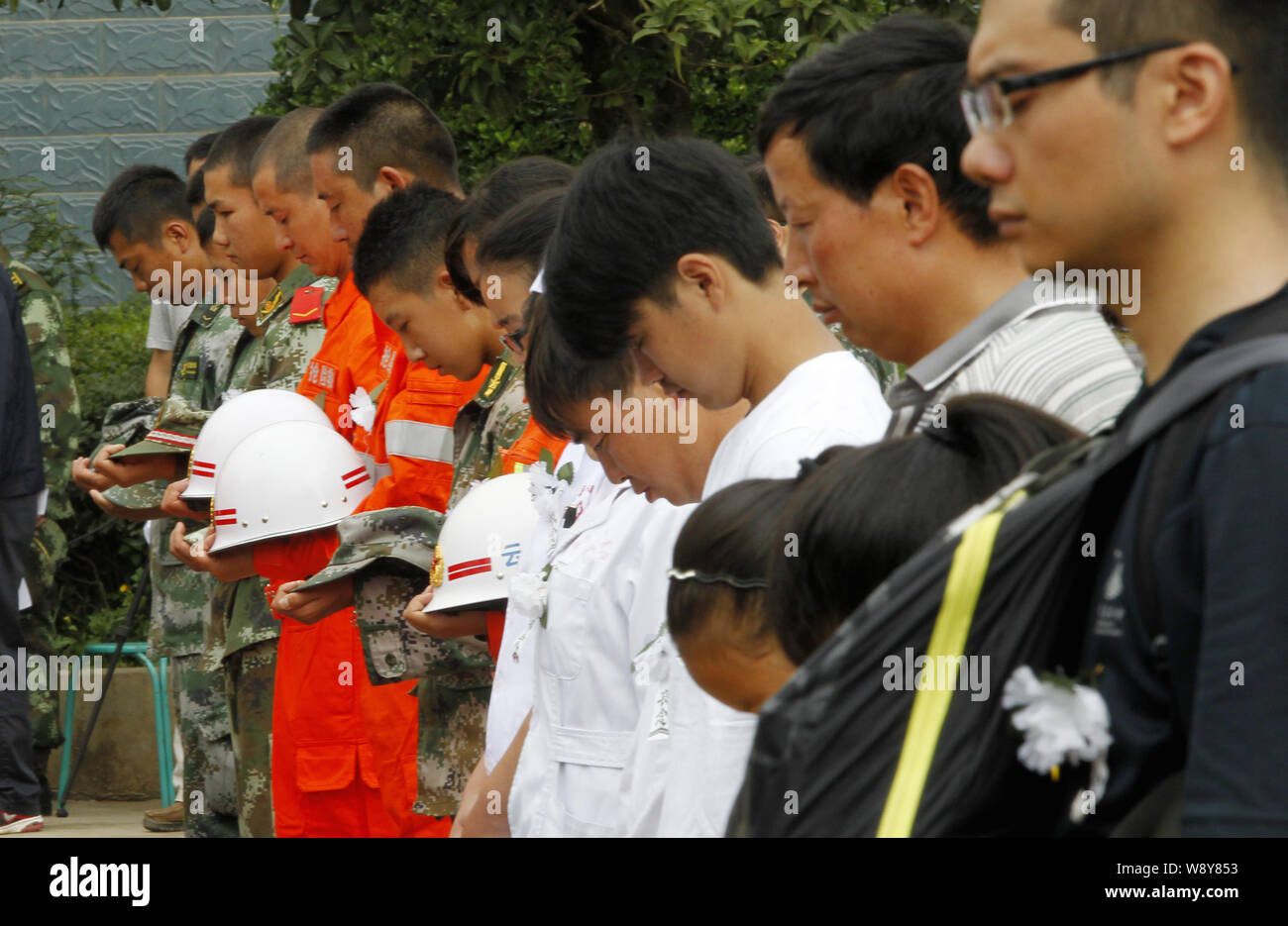 I soccorritori cinesi e residenti locali osservare tre minuti di silenzio per piangere le vittime del 6,5-terremoto di magnitudine durante un pubblico lutto ev Foto Stock