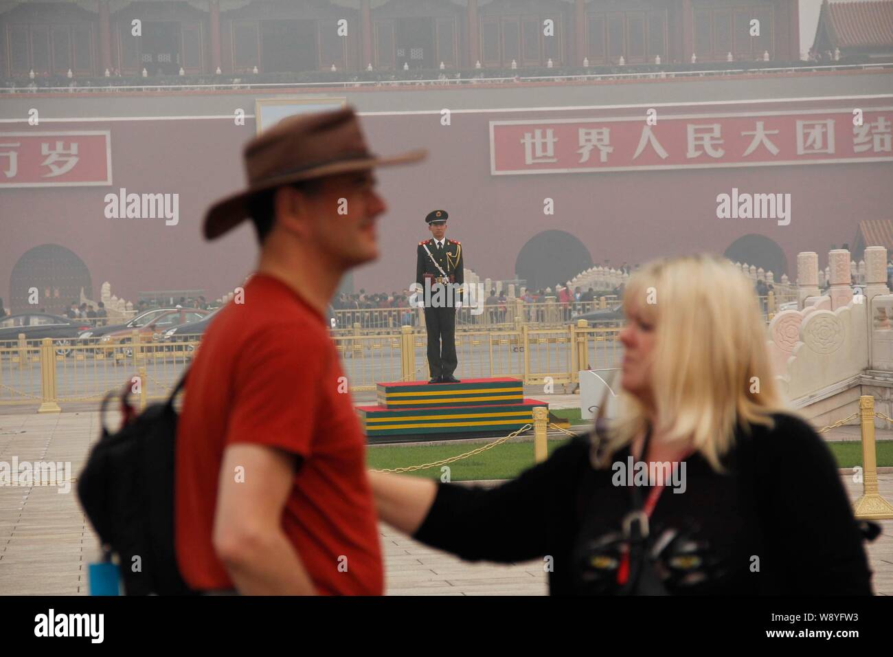 I turisti stranieri a piedi passato un poliziotto paramilitari di guardia sulla piazza Tiananmen in pesanti smog a Pechino, in Cina, il 9 ottobre 2014. Pechino Foto Stock