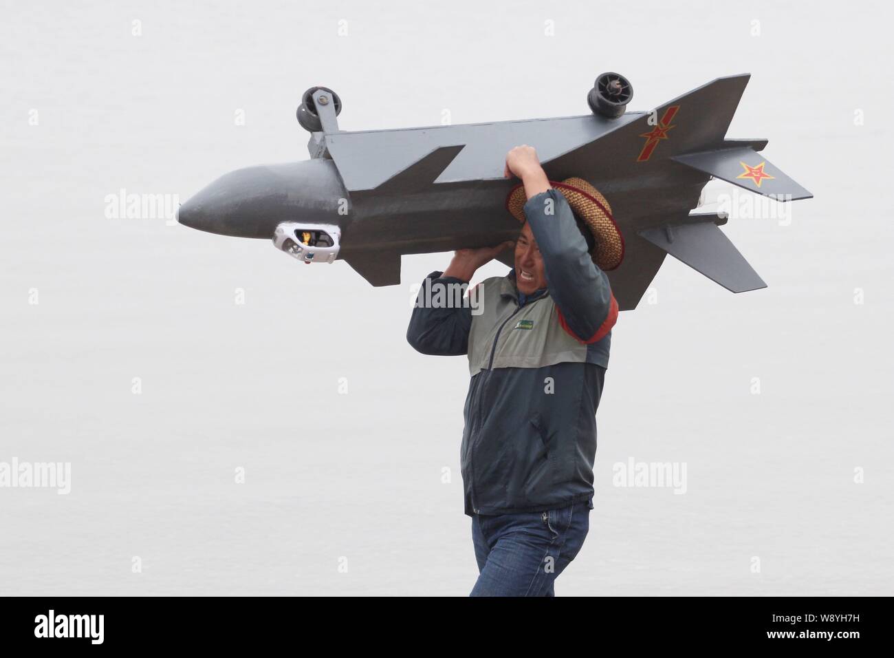 Un lavoratore svolge un modello di J-20 Stealth Fighter realizzato da 80-anno-vecchio Wen Yuzhu prima di metterla sul suo modello artigianale di porcellane primo aeromobile ca Foto Stock