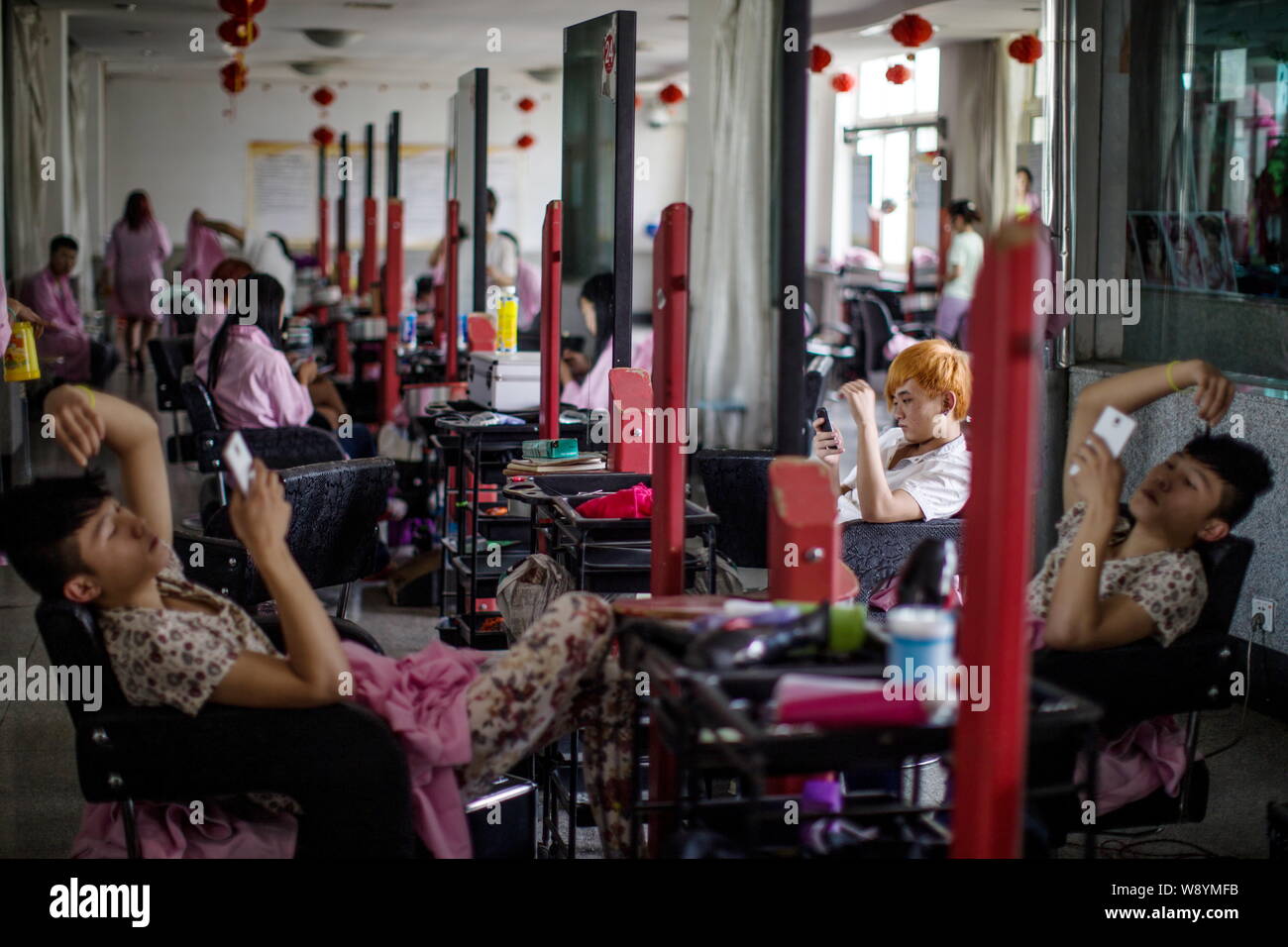 Studenti Cinesi utilizzare il loro smartphone dopo la finitura di una classe di parrucchiere a Lanxiang Vocational School di Jinan City East Chinas provincia di Shandong Foto Stock