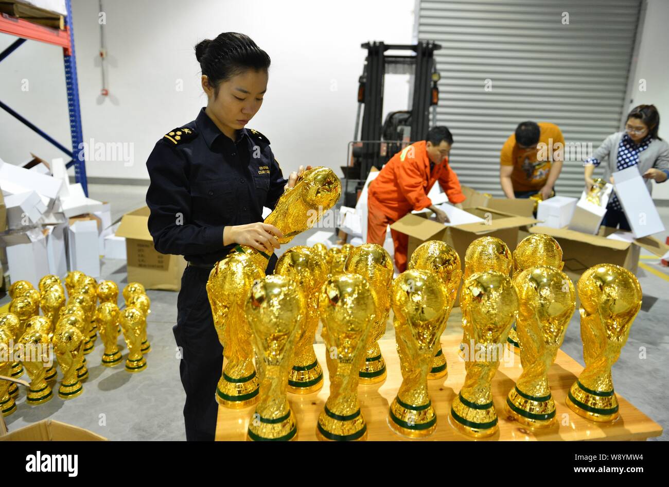 Un Cinese funzionario doganale verifica sequestrati fake World Cup trofei in corrispondenza di un magazzino in Yiwu City East Chinas nella provincia di Zhejiang, 16 aprile 2014. Più di Foto Stock