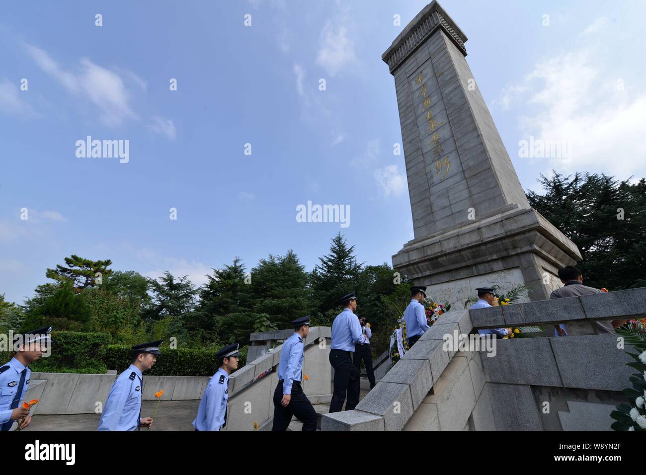 Poliziotti cinesi presenti fiori in un monumento al primo dei martiri giorno nella città di Bengbu, est cinese della provincia di Anhui, 30 settembre 2014. Un da Foto Stock