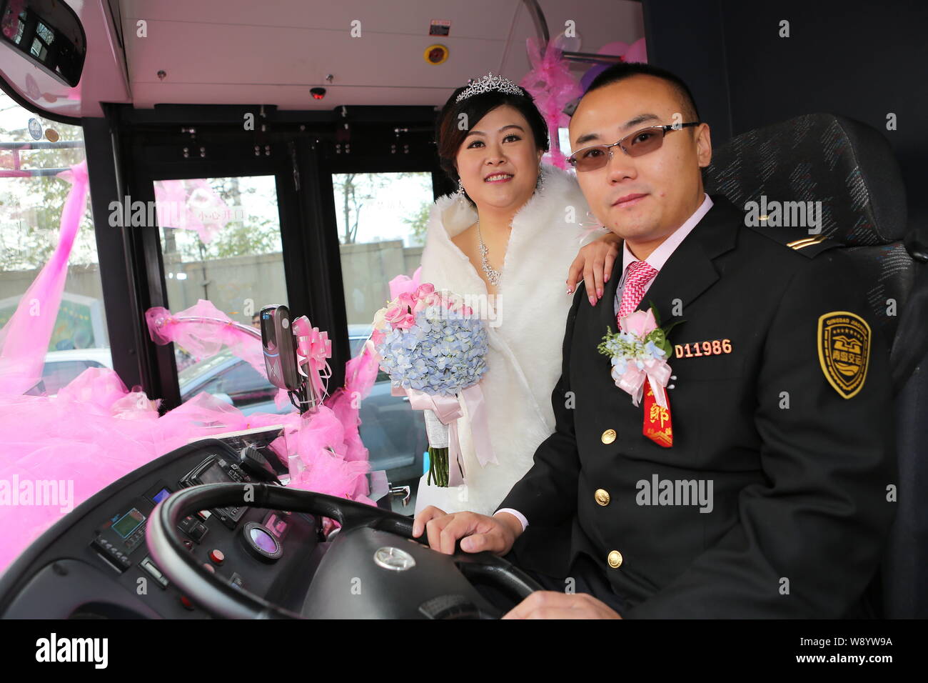 Cinese del driver bus Lu Jia, destra e la sua sposa Li Ning pongono in bendy bus come il loro matrimonio veicolo nella città di Qingdao, Cina orientale della provincia di Shandong, Foto Stock