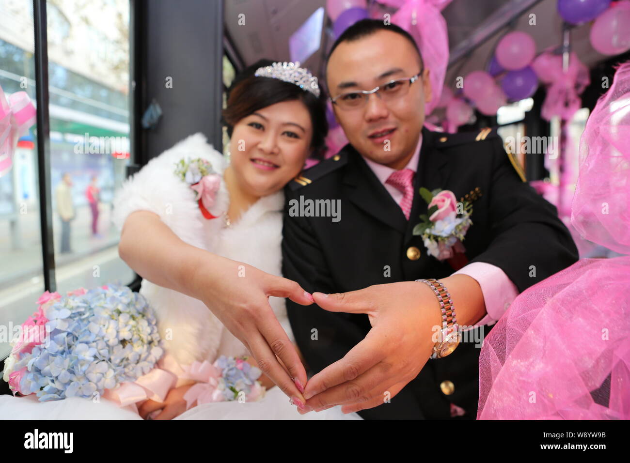 Cinese del driver bus Lu Jia, destra e la sua sposa Li Ning pongono in bendy bus come il loro matrimonio veicolo nella città di Qingdao, Cina orientale della provincia di Shandong, Foto Stock