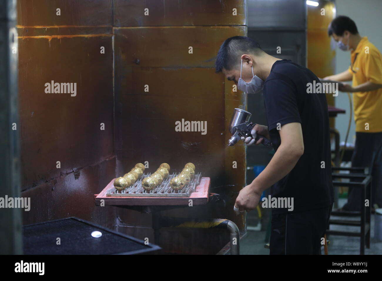 Un lavoratore cinese spray-pitture miniatura della Coppa del Mondo FIFA trofei in fabbrica di Dongguan carro oggettistica Co., Ltd. in Dongguan City, a sud Chinas gua Foto Stock