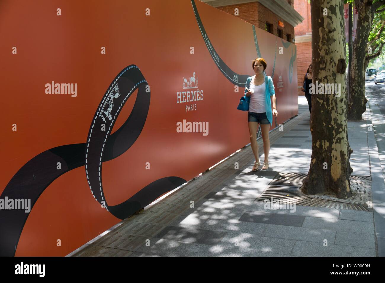 I pedoni a piedi passato un annuncio per un ben presto aprire flagship store di Hermes su Huahai Road a Shanghai in Cina, 13 agosto 2014. Iconico francese Foto Stock