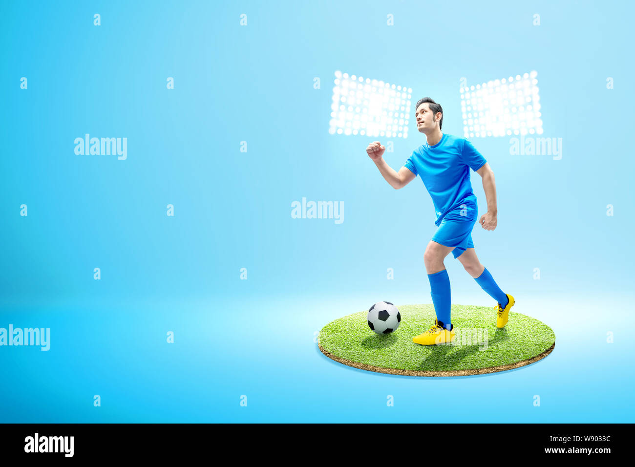 Asian giocatore di football uomo correre con la palla sul campo di calcio con faretti Foto Stock