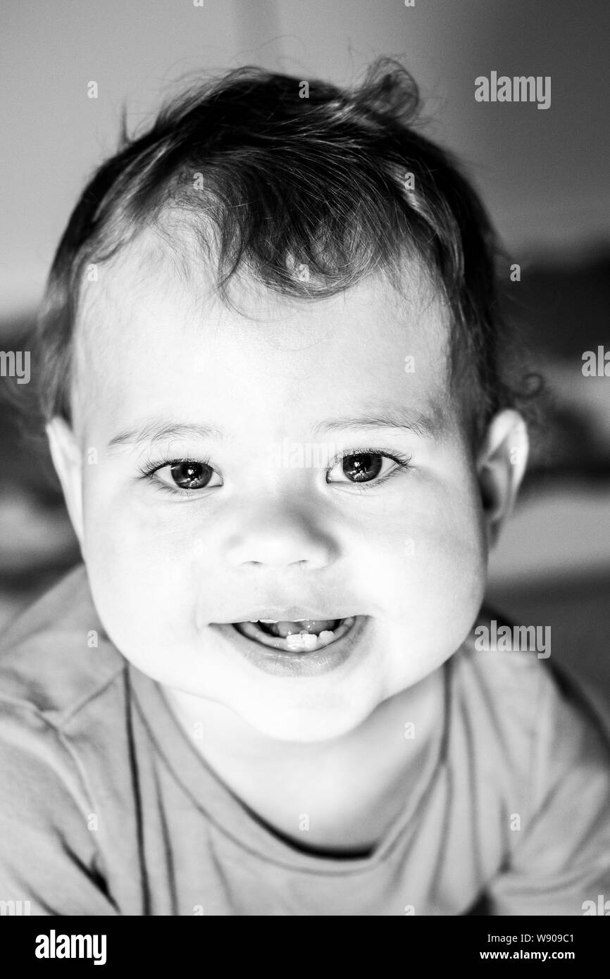 Ritratto di bambino in bianco e nero closeup. Il Toddler ragazza ragazzo dieci mesi sorridente, denti visibile, allegro Laughing baby teething. Bel bambino Foto Stock