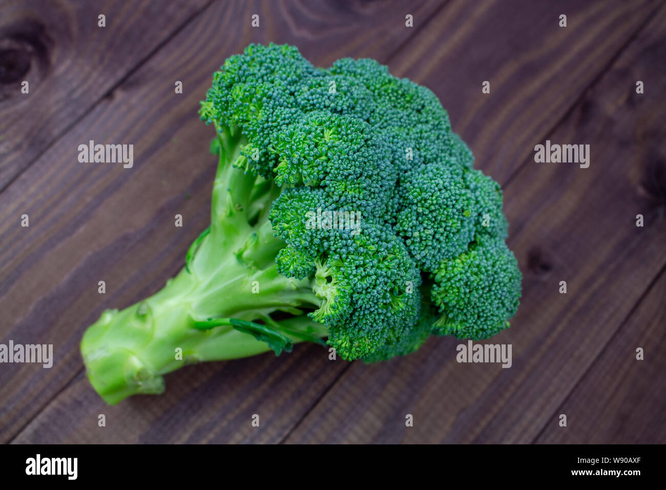 Un ramo di broccoli verdi al buio su un tavolo di legno. Stuzzicanti fresco verde broccoli, Smeraldo ciuffi di foglie poco broccoli. Vegetariano vegano ve fresca Foto Stock