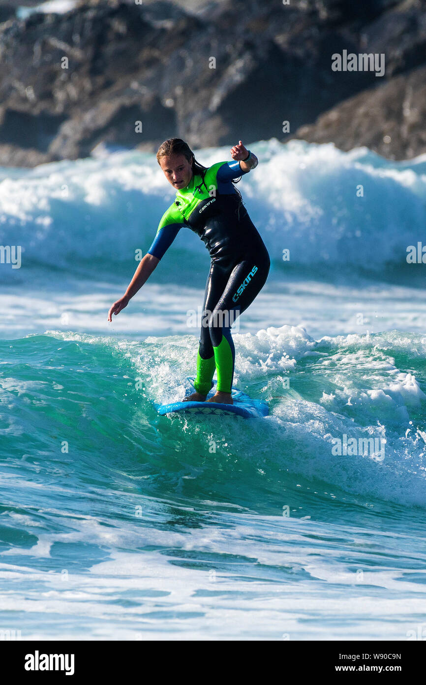 Un surfista femmina a cavallo di un onda al Fistral a Newquay in Cornovaglia. Foto Stock