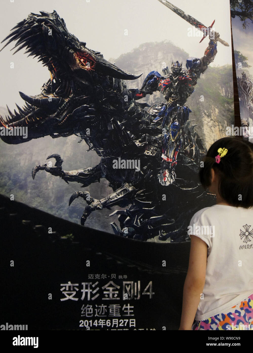 Una ragazza guarda un poster per film di Hollywood, trasformatori: Età di estinzione, in un cinema della città Yichang, porcellane centrale provincia di Hubei, 2 Luglio 2014 Foto Stock