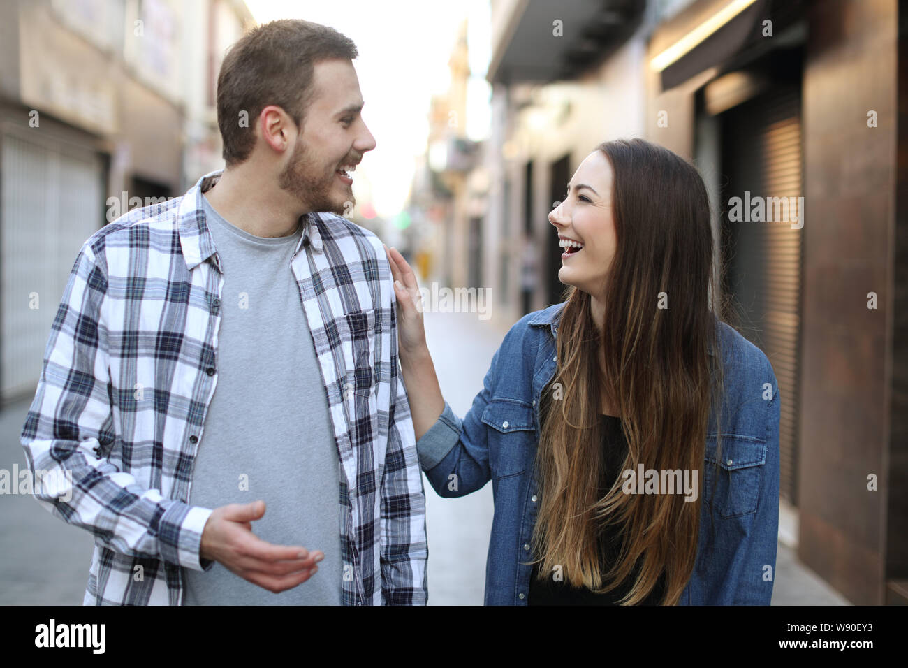 Vista anteriore verticale di un felice amici flirtare camminando verso di voi per la strada Foto Stock