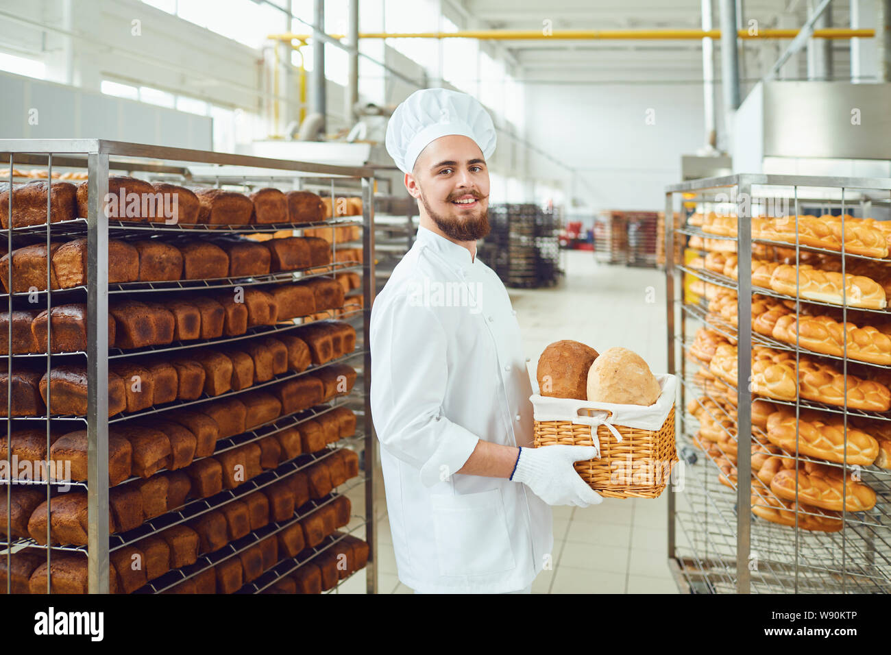 Barbuto baker sorride tenendo un cesto di pane presso il bakehouse Foto Stock