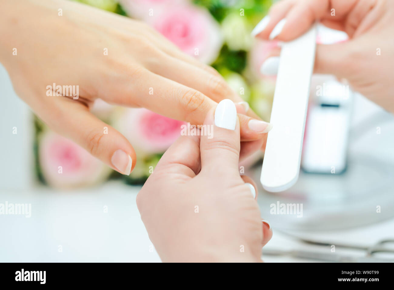 Le mani di un qualificato manicurist il deposito delle unghie di una giovane donna Foto Stock