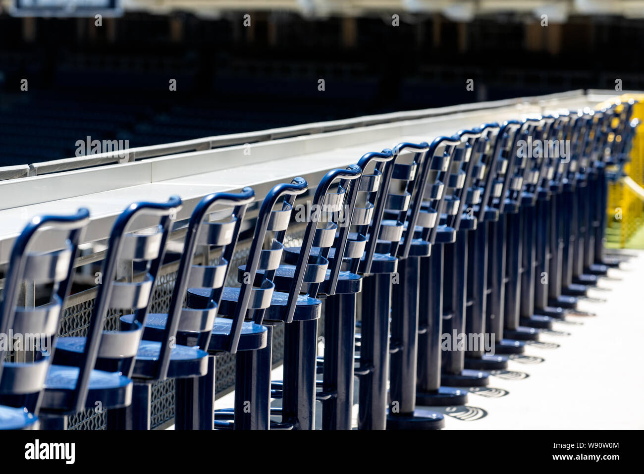 Fila rettilinea di alti sgabelli e bancone per gli appassionati di baseball per sedersi e guardare la partita allo stadio dal pianale superiore. Foto Stock