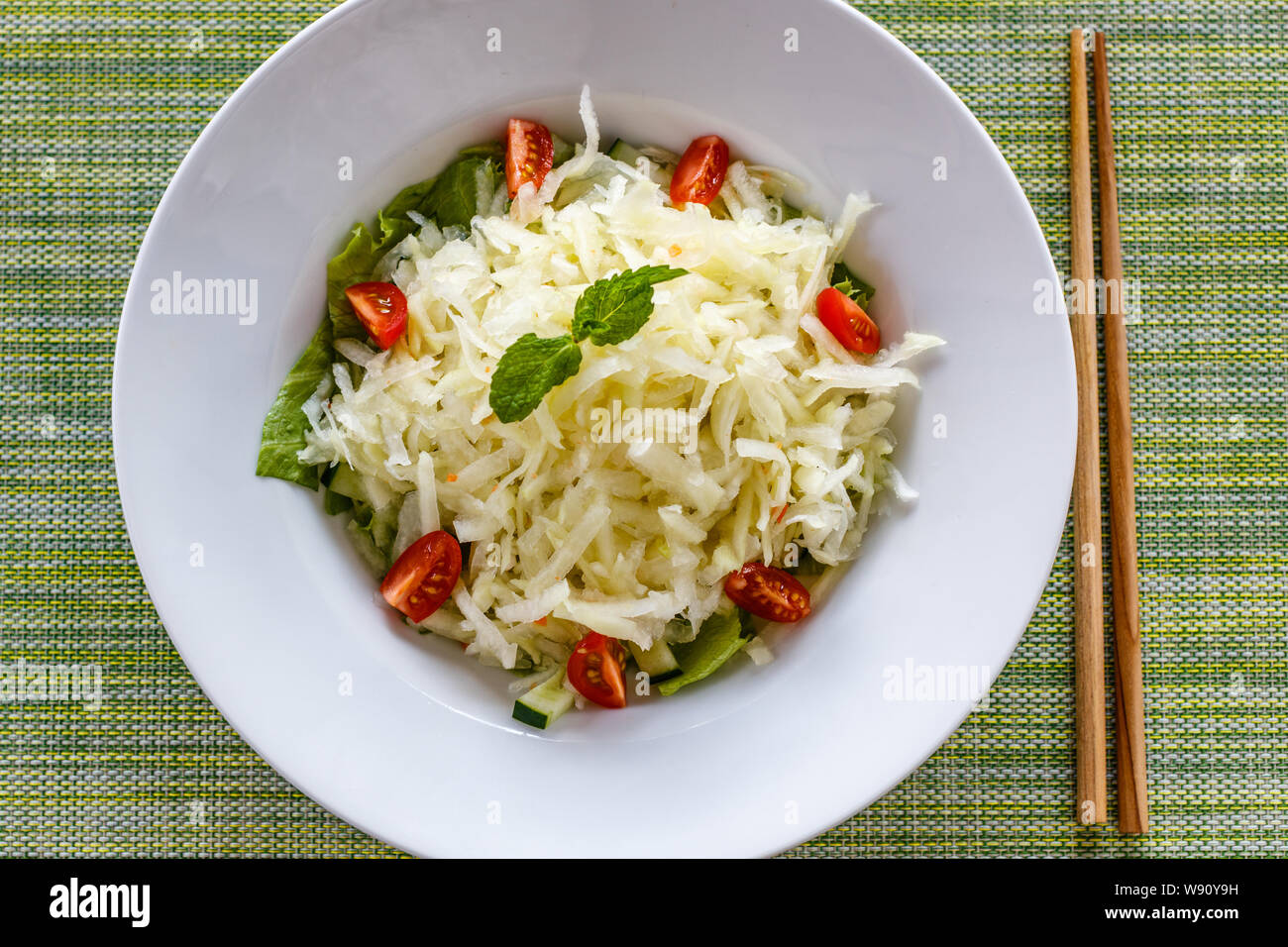 Thai piccante insalata di papaia Tam Som. Sfondo verde, bacchette sul lato. Quisine tradizionale della Thailandia e Laos. Foto Stock