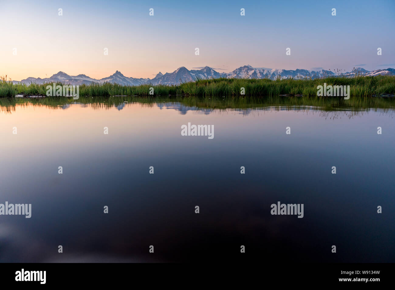 Eiger, Mönch und Jungfrau spiegeln sich in kleinem Tümpel im Morgenrot Foto Stock