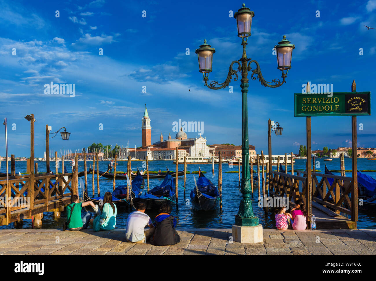 Visite a Venezia. I turisti seduti sul lungomare potrete ammirare il famoso St George Island e laguna veneziana Foto Stock