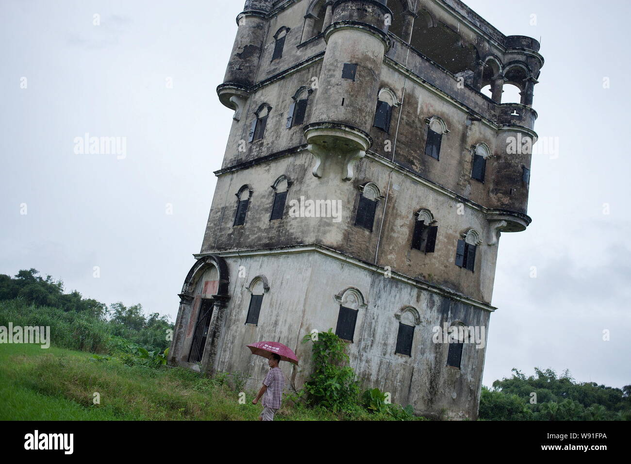 --FILE--cinese abitante Guan Woqiang passeggiate passato un del Kaiping Diaolou torre di avvistamento utilizzato per stock fieno nel villaggio di vuoto di Fuheli, del Kaiping, Jiangmen city Foto Stock