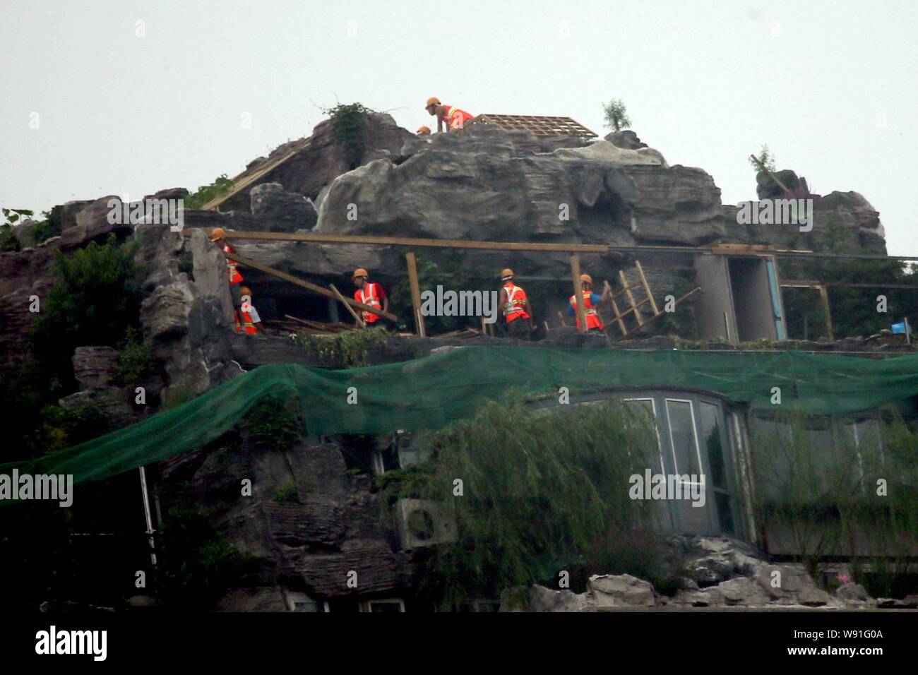 Lavoratori cinesi ad abbattere il giardino di roccia in cima villa che è costruito dal professor Zhang Beiqing sul tetto del suo edificio di appartamenti in Foto Stock