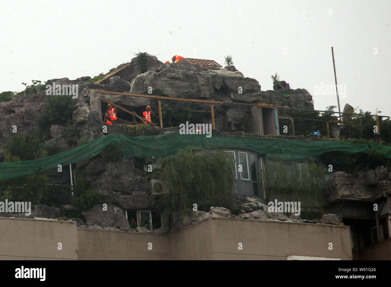 Lavoratori cinesi iniziare ad abbattere il giardino di roccia in cima villa che è costruito dal professor Zhang Beiqing sul tetto del suo appartamento bui Foto Stock