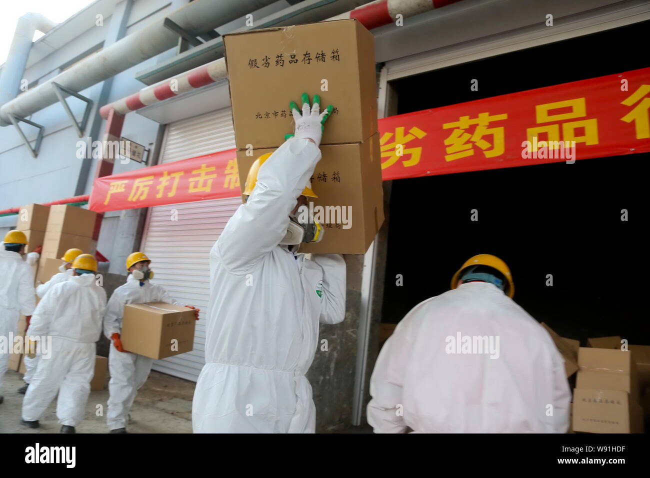 Lavoratori mascherato cartoni di trasporto di farmaci contraffatti per essere distrutti in un impianto a Pechino in Cina, 14 marzo 2013. Farmaco cinesi competenti destroye Foto Stock
