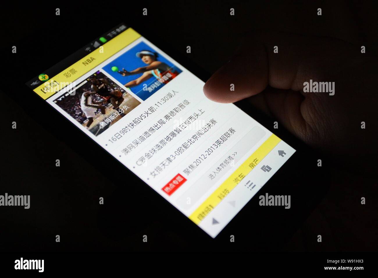 --FILE--Una persona utilizza uno smartphone per navigare in un sport news sito web in Nantong, est Chinas provincia dello Jiangsu, 15 gennaio 2013. Quasi il 80 percento di C Foto Stock