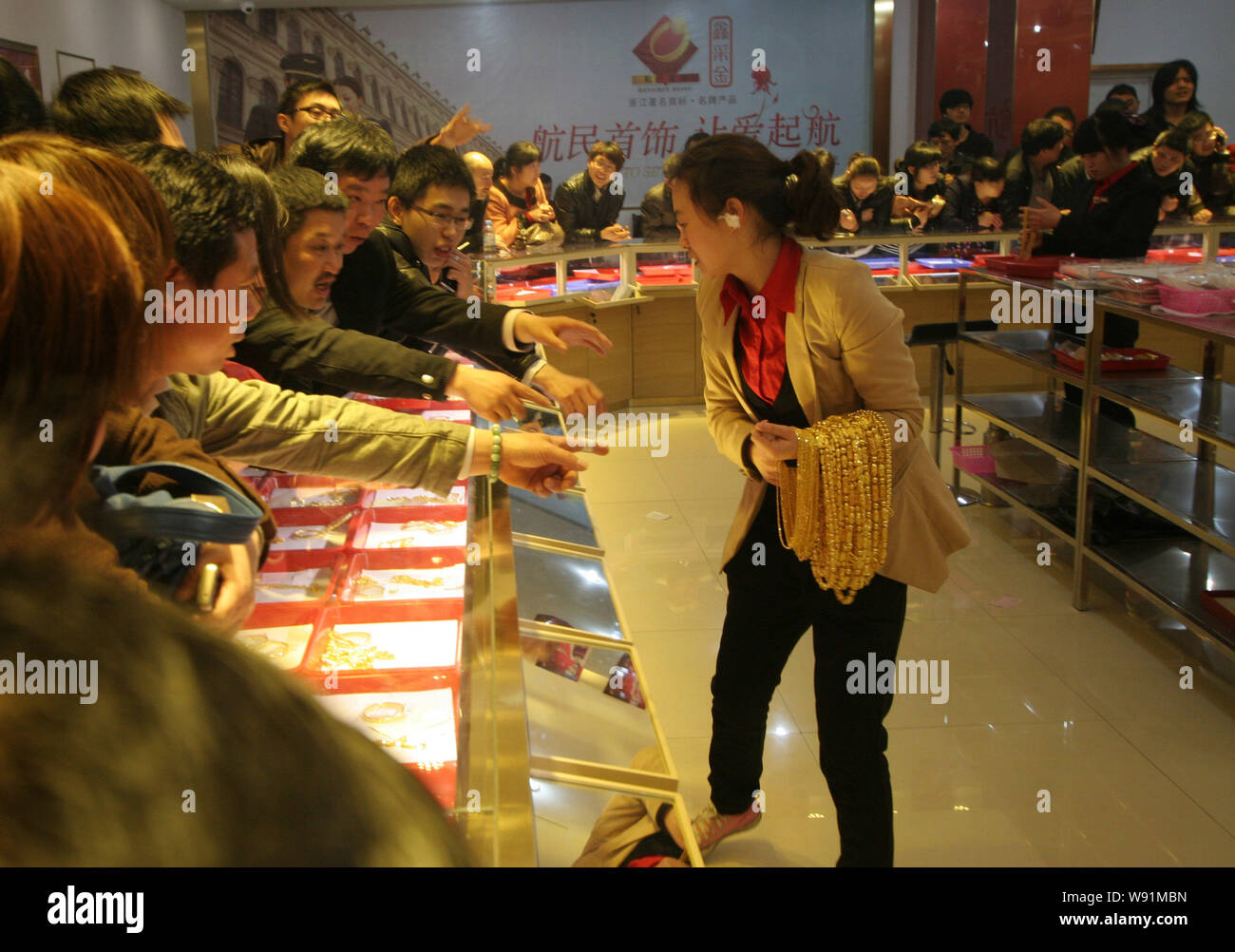 Un addetto cinese porta collane d'oro come cifrare i clienti ad acquistare ornamenti d'oro presso un negozio gioielli in Hangzhou, est Chinas nella provincia di Zhejiang, Foto Stock