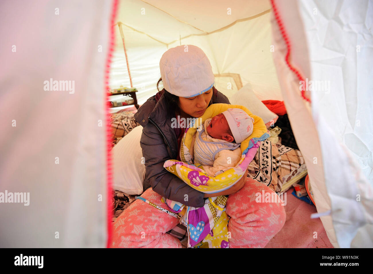 Una madre cinese si prende cura del suo neonato in una tenda di soccorso all indomani della 7,0-terremoto di magnitudine nel villaggio di Qinglong, contea di Lushan, Foto Stock