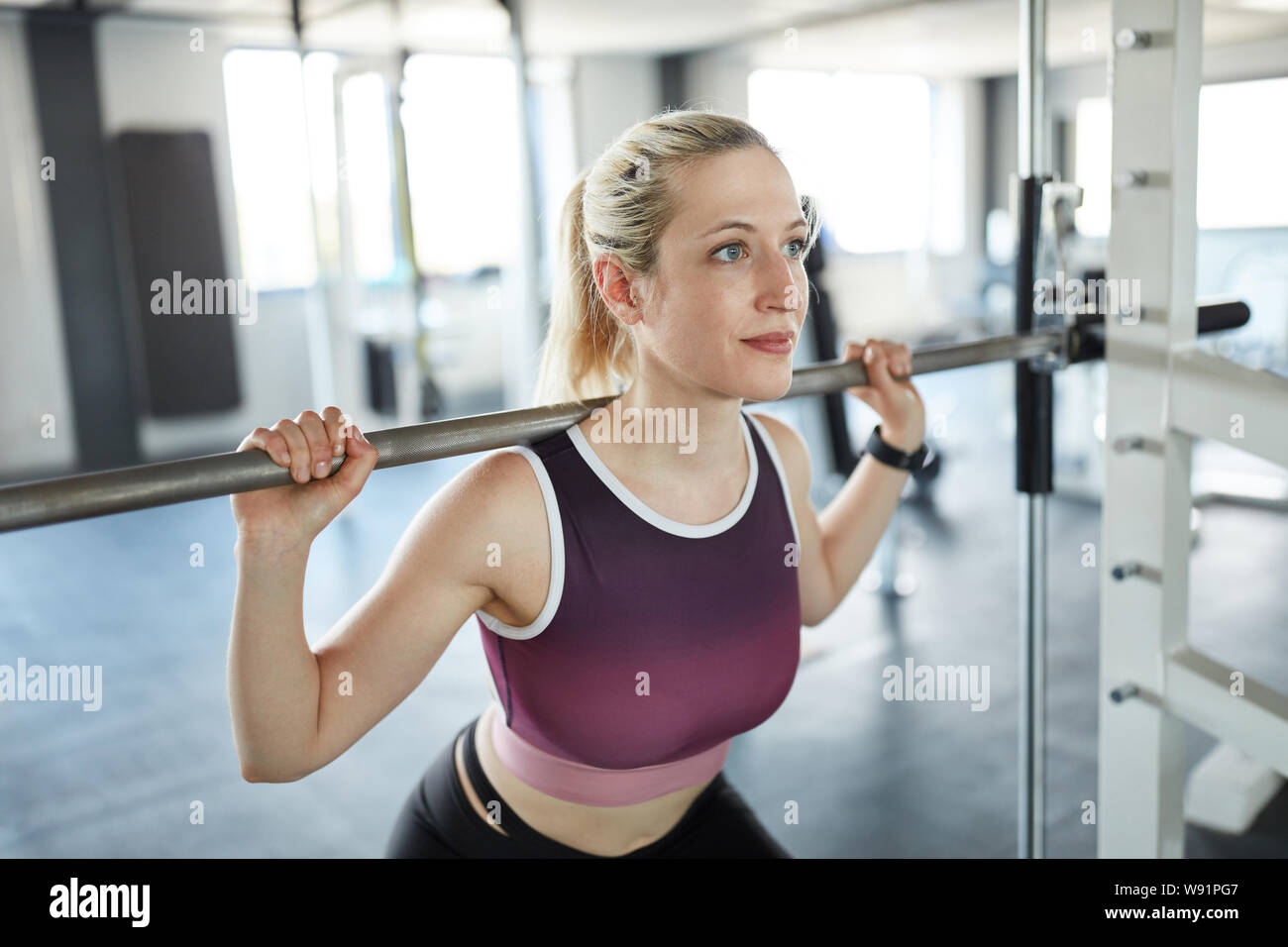 Sporty giovane donna allenamento dei muscoli delle gambe in barbell station Foto Stock