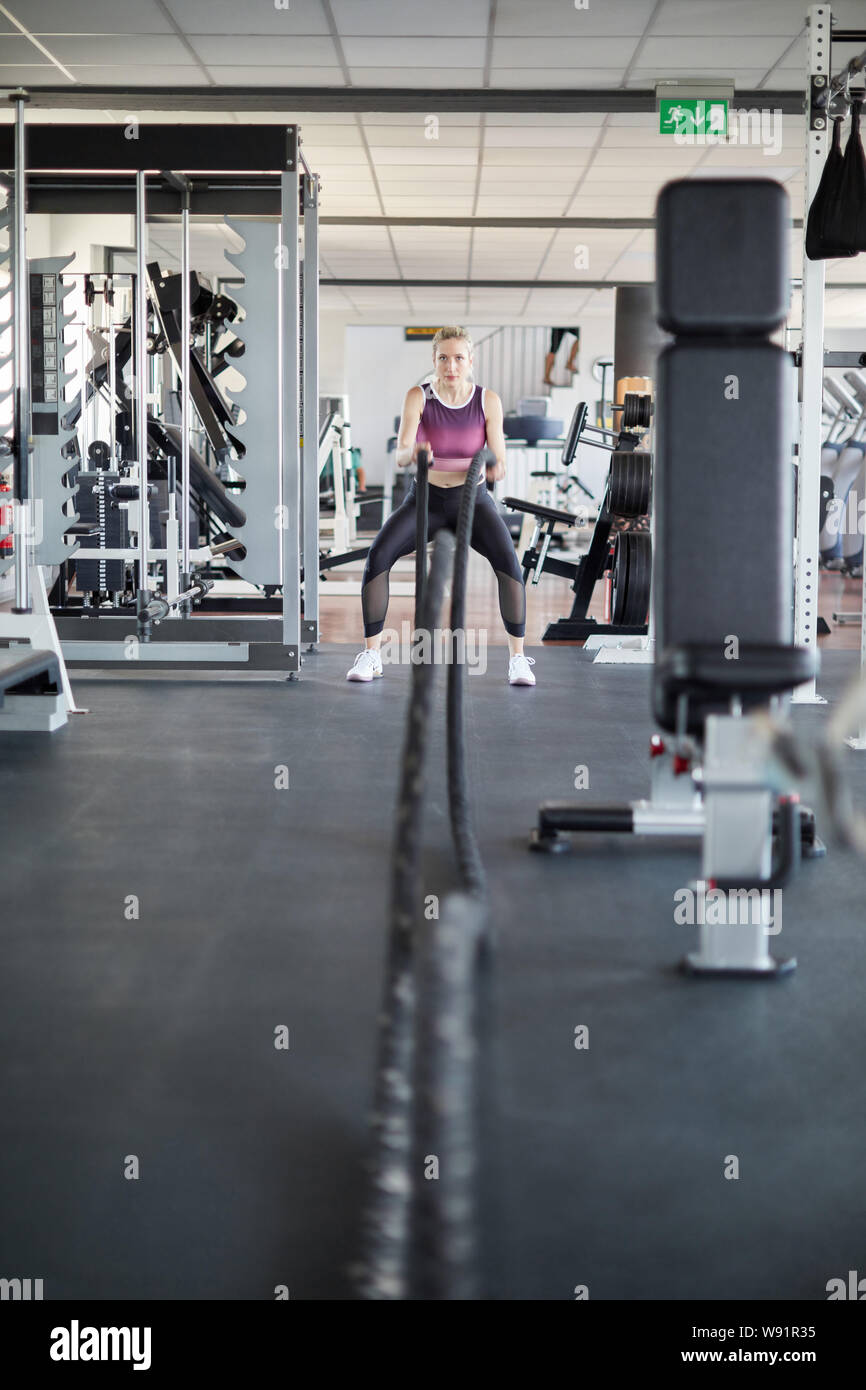 Giovane donna treni endurance di forza e abilità con la corda di battaglia Foto Stock