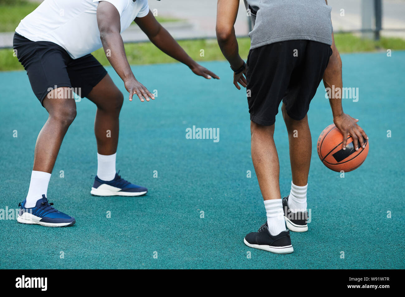 Vista posteriore basso angolo di afro-americano di due ragazzi giocare a basket all'aperto, spazio di copia Foto Stock