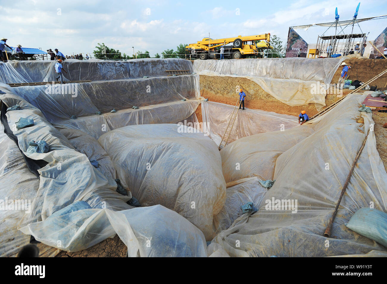 Lavoratori cinesi dal locale Dipartimento di Archeologia di coprire una fossa sacrificale con membrana plastica presso il Cimitero di Yejiashan del Western Zhou Dyn Foto Stock