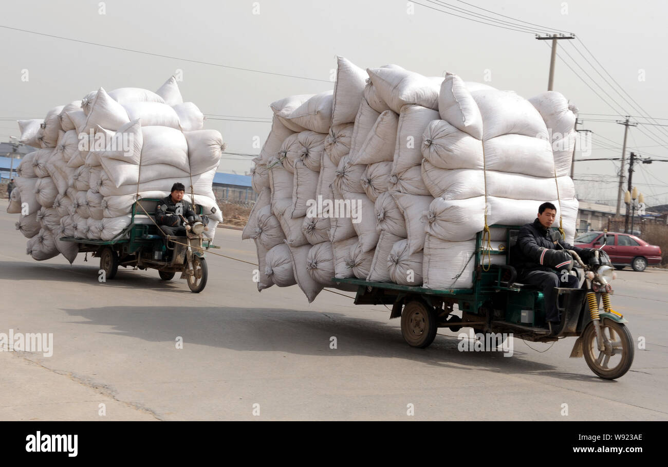 Due tricicli a motore sovraccaricato con sacchi di merci ride su China National Highway 107 nella contea di Zhengding, porcellane del nord nella provincia di Hebei, 21 marzo 2010. Foto Stock