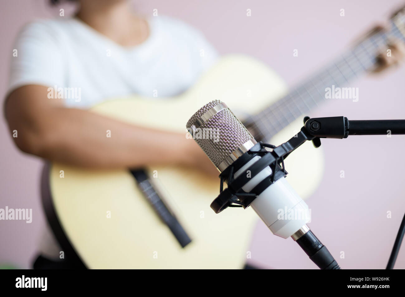 Donna asiatica giocare chitarra acustica per il jazz e la musica di facile ascolto brano e registrare con il microfono selezionare focus leggera profondità di campo Foto Stock