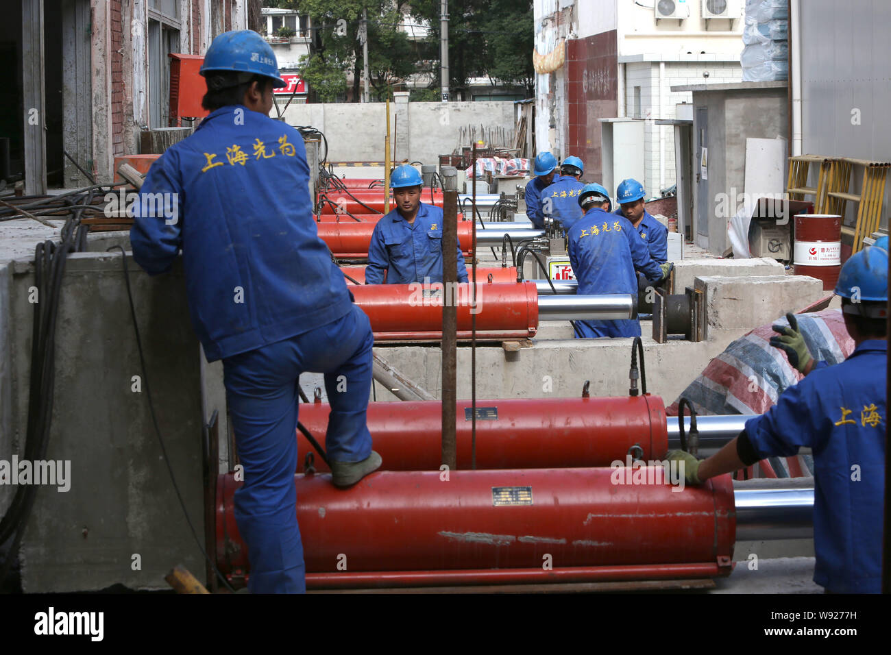 Lavoratori regolare la pressione idraulica dei martinetti in preparazione per il passaggio della 78-anno-vecchio a sei piani edificio Zhengguanghe in Cina a Shanghai, 1 novembre Foto Stock