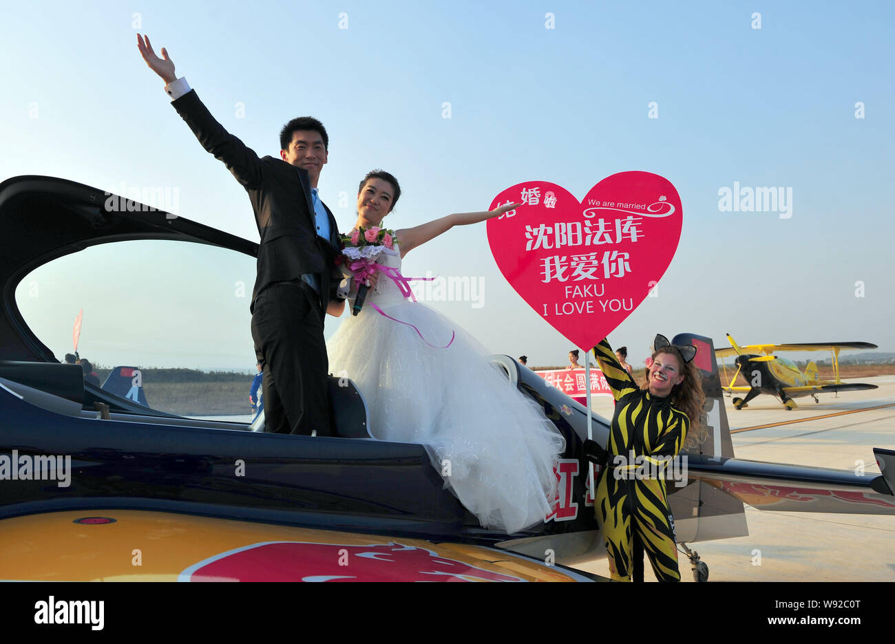 Sposi novelli pongono su un piano in corrispondenza della cerimonia nuziale che ha tenuto presso il giorno di chiusura del AOPA-Cina Fly-In 2013 air show in Faku Caihu aeroporto in Shenya Foto Stock