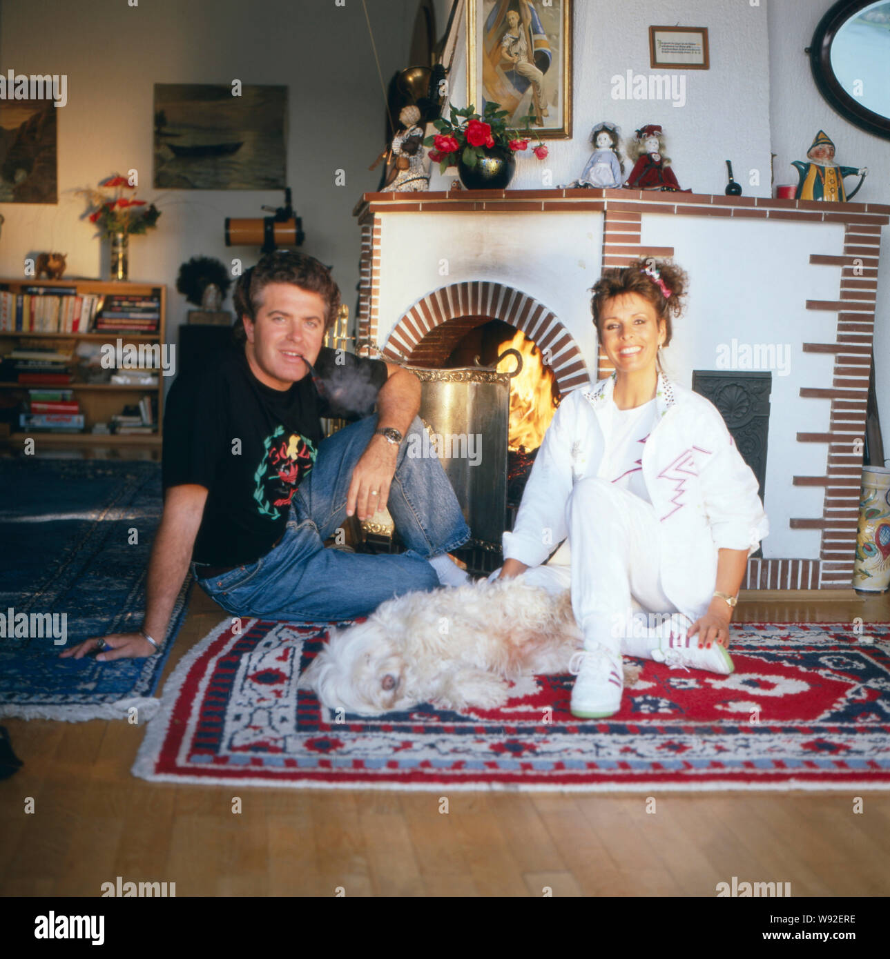 Die deusch-britische Schlagersängerin Ireen Sheer mit ihrem Ehemann Gavin du Porter posieren vor einem Kamin, ca. 1988. L'anglo-tedesco cantante pop Ireen Sheer e suo marito Gavin du Porter pongono davanti a un caminetto, ca. 1988. Foto Stock