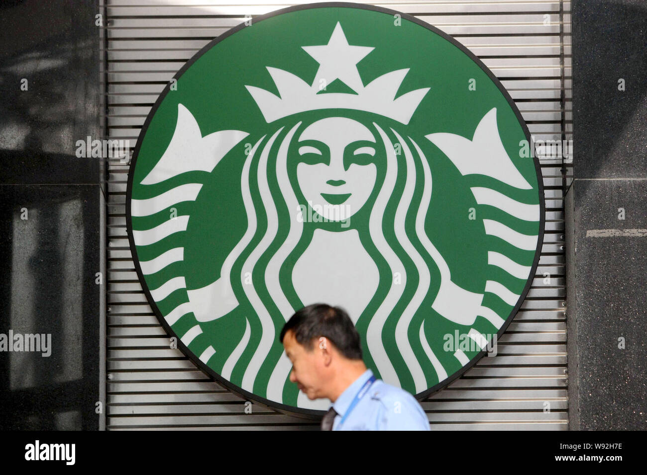 Una passeggiate a piedi passato un logo di caffè Starbucks in Cina a Shanghai, 9 ottobre 2013. Noi della catena di caffè Starbucks Corp. vide margine operativo r Foto Stock