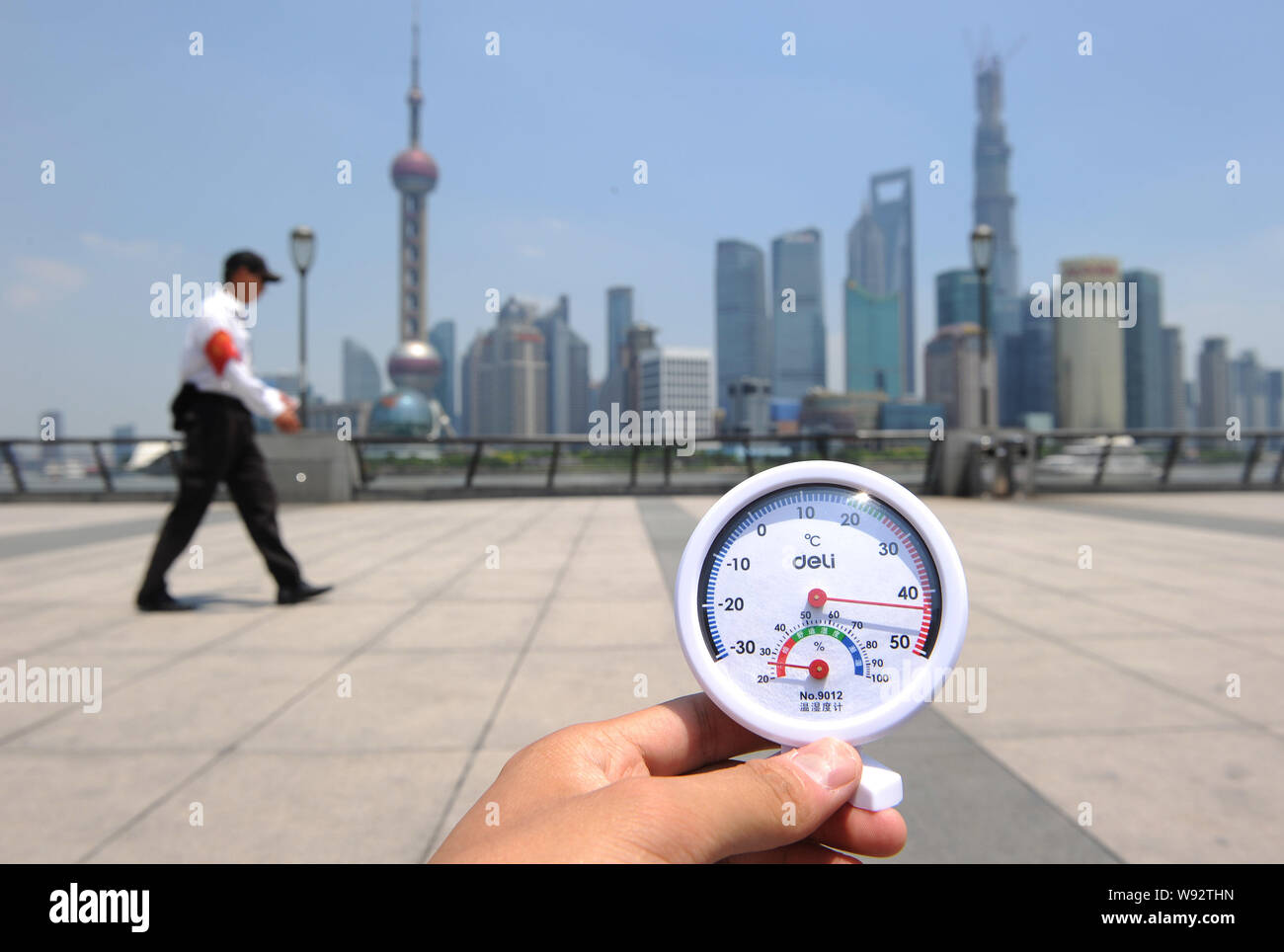 Una guardia di sicurezza è in servizio sotto il sole cocente lungo il Bund come un termometro visualizza la temperatura raggiunge 42 gradi Celsius a Shanghai, Chi Foto Stock