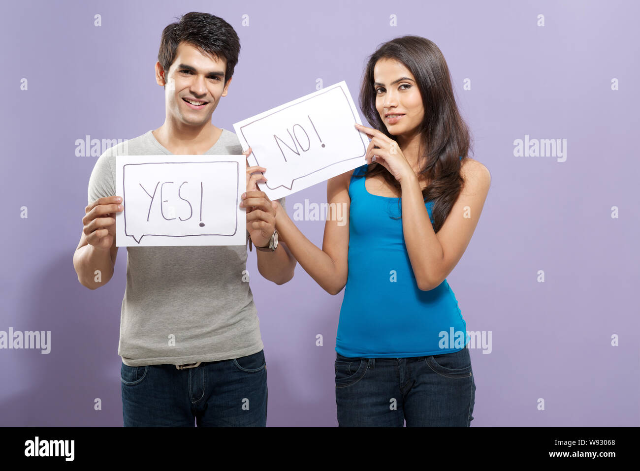 Coppia giovane che mostra il foglio di carta scritto sì e no Foto Stock