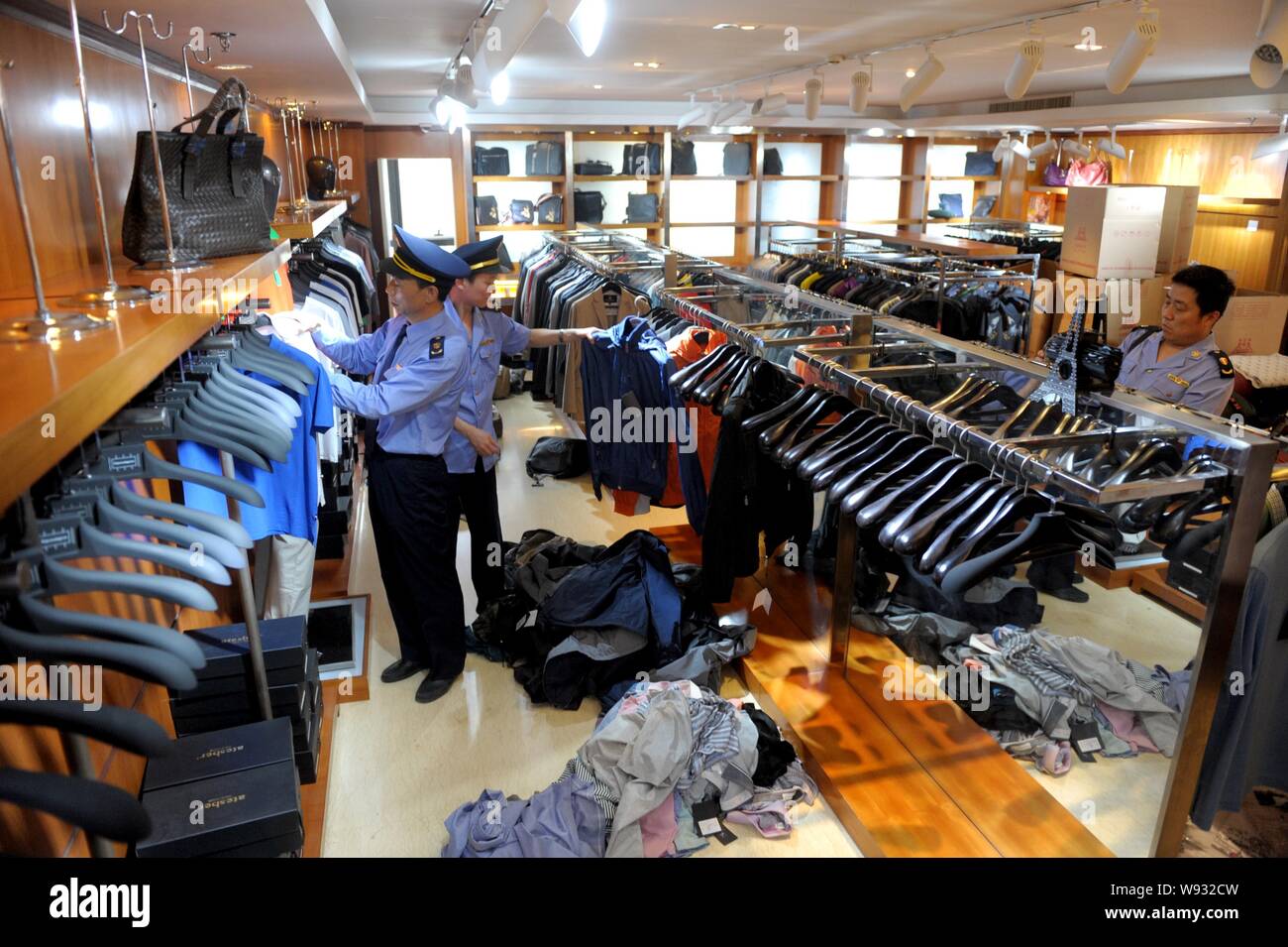La legge cinese i funzionari di polizia confiscare fake luxury beni di marca in un negozio a Pechino, in Cina, il 13 maggio 2013. La polizia di Pechino e di applicazione della legge off Foto Stock