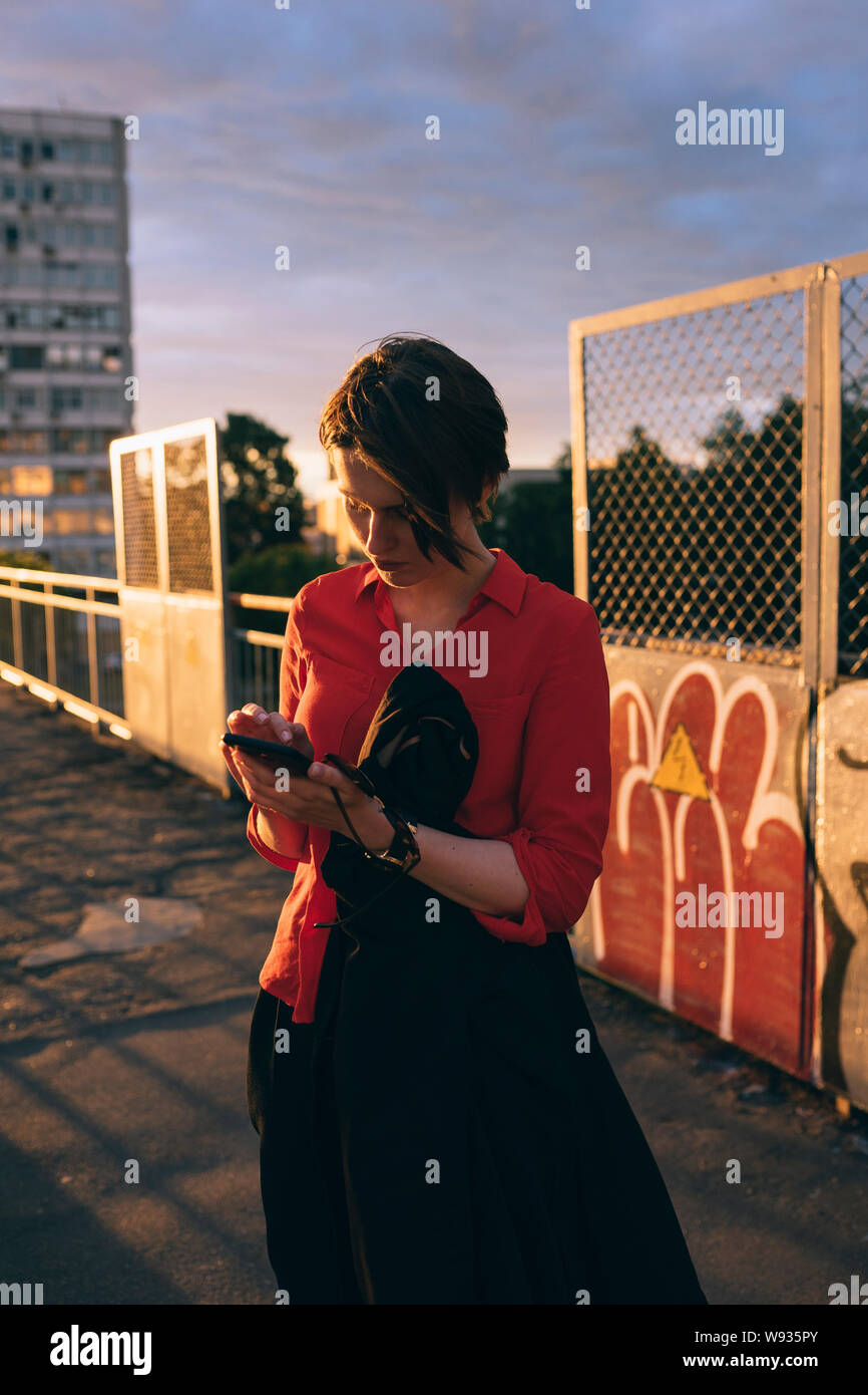 Donna con telefoni in mano compone il numero durante il tramonto Foto Stock