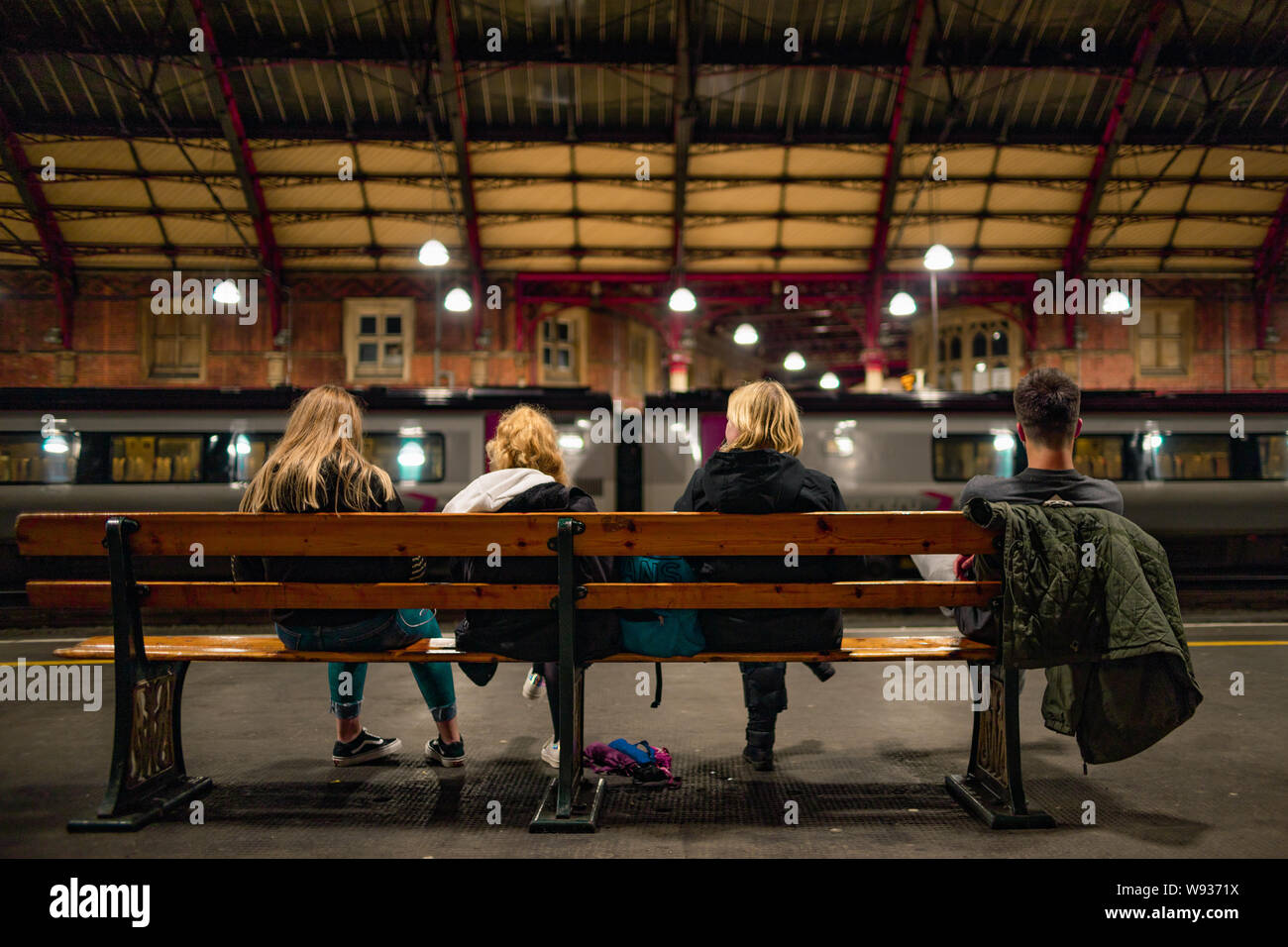 Seduto persone in attesa presso la stazione ferroviaria di Temple Meads Bristol Foto Stock