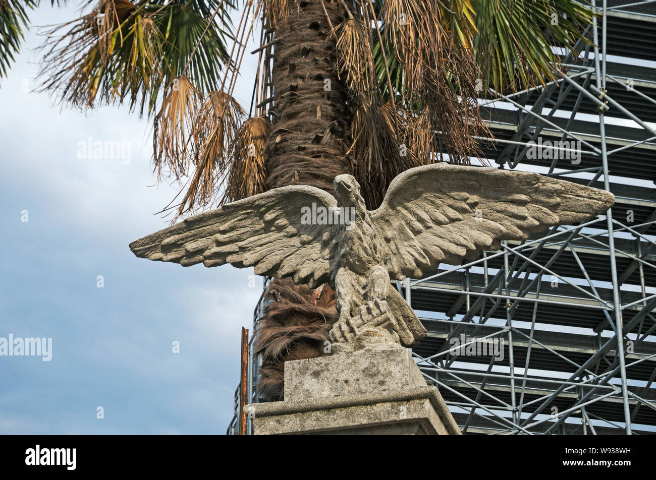 Un antico in pietra scultura eagle sotto una palma all'ingresso di uno stadio, Italia Foto Stock