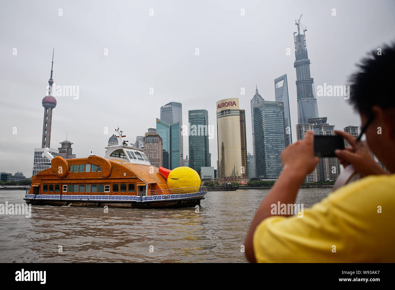 Un uomo cinese prende le foto del traghetto, che ha adattato il design dell'Florentijn Hofmans Rubber Duck sul fiume Huangpu a Shanghai in Cina, 26 Au Foto Stock