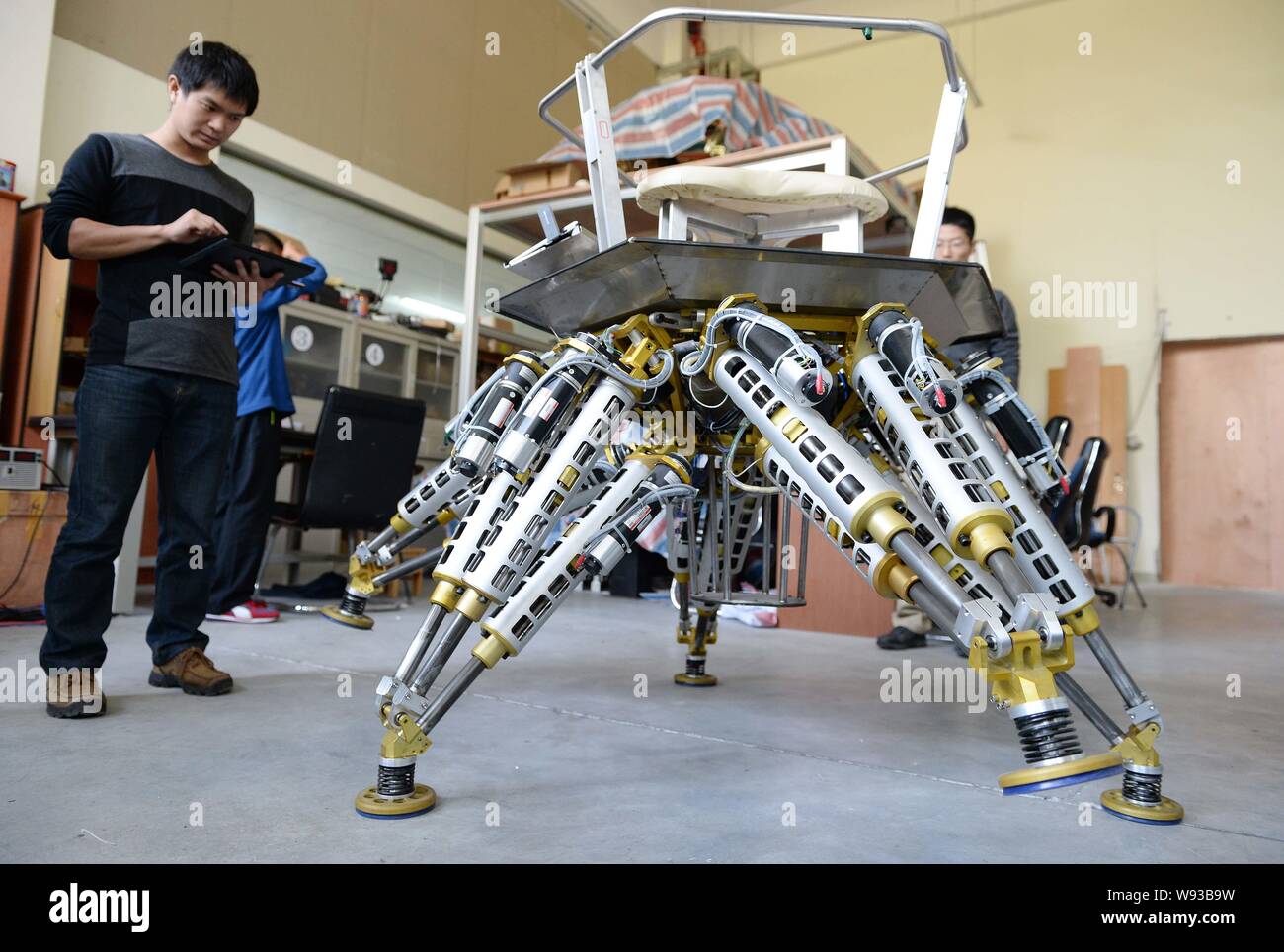 Un maschio di studente cinese-remoto controlla una a sei zampe robot di salvataggio presso la Scuola di Ingegneria Meccanica di Shanghai Jiao Tong University di Shanghai, Foto Stock