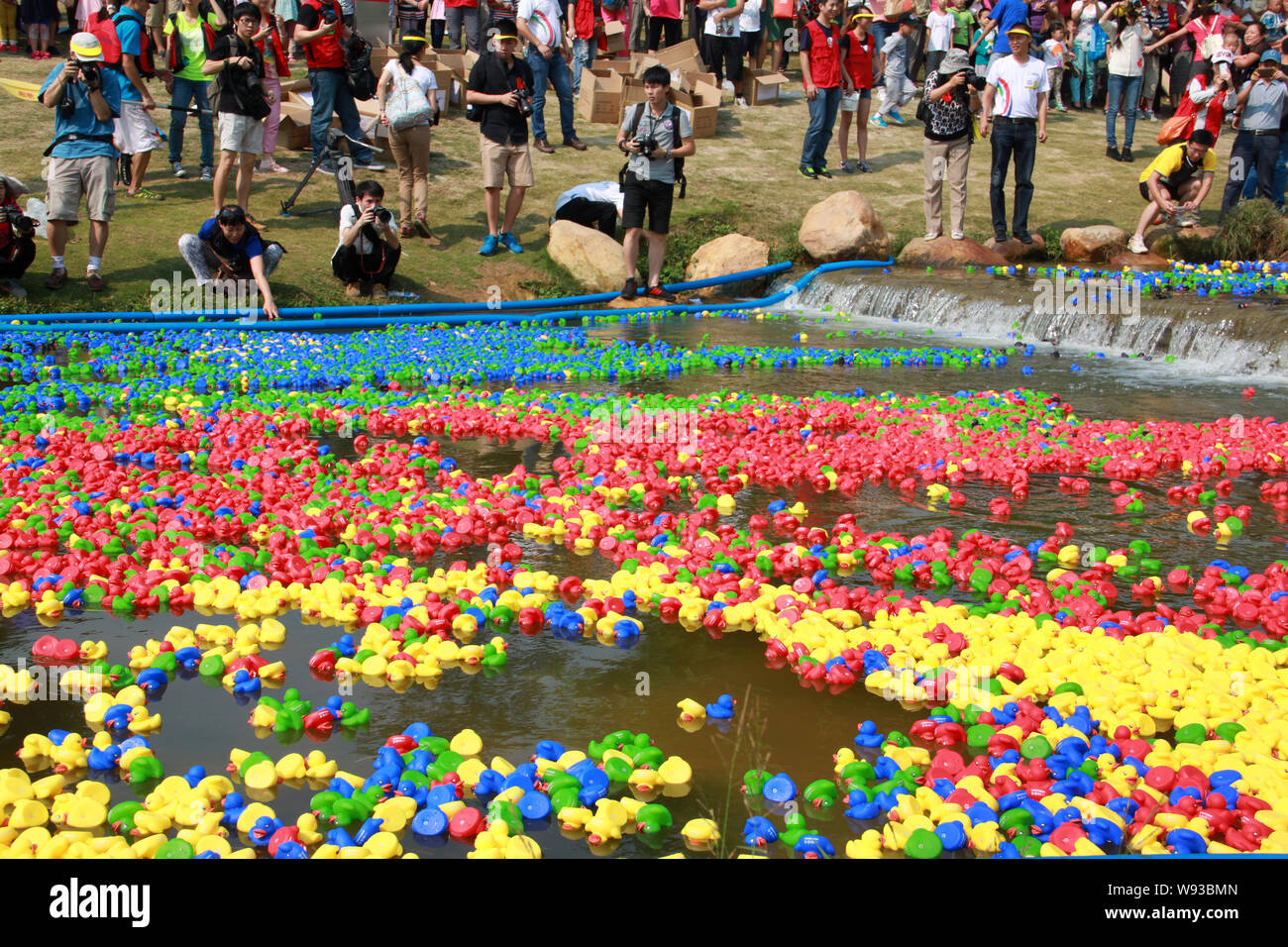 I residenti locali di guardare e scattare foto di gomma anatre drifting lungo il fiume di Futian durante un evento di beneficenza a Shenzhen Central Park nella città di Shenzhen, così Foto Stock